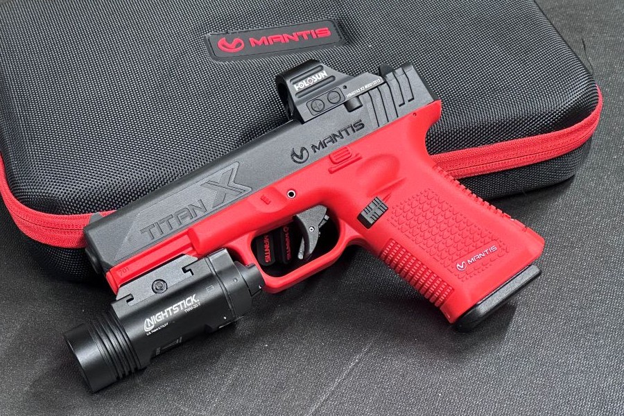 An orange and black training pistol with a light and optic attached to it. 