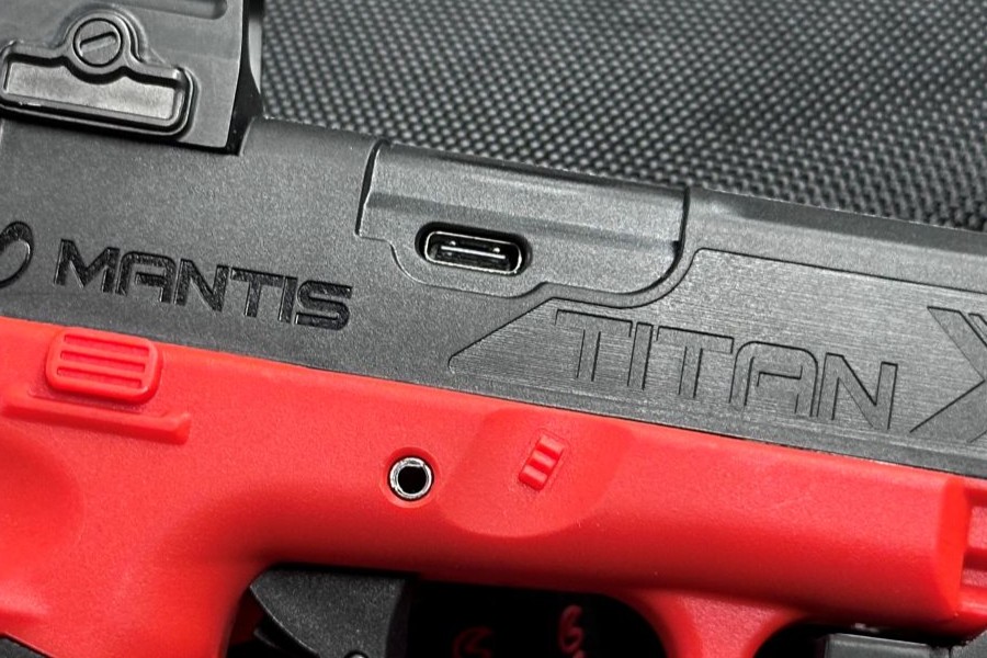 The side of a training pistol, revealing a charging port in the slide. 