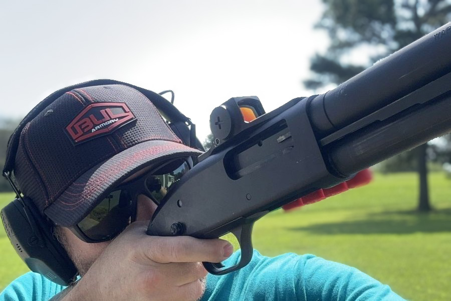 A person shooting a shotgun with a Vortex Viper red dot sight attached.
